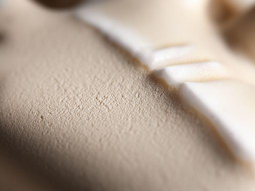 Nahaufnahme einer handgeformten Keramikoberfläche mit feiner Struktur und heller Glasurkante
